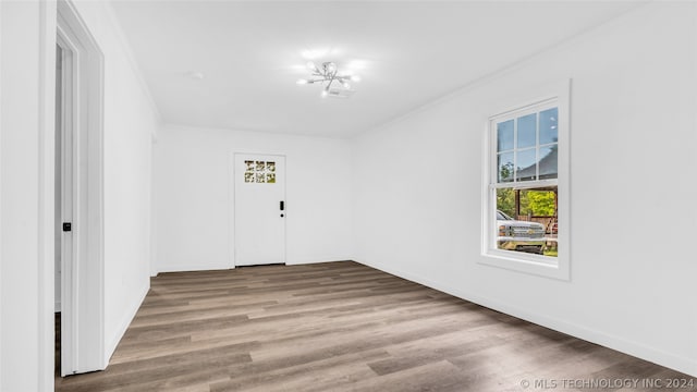 unfurnished room with ornamental molding, wood-type flooring, and an inviting chandelier