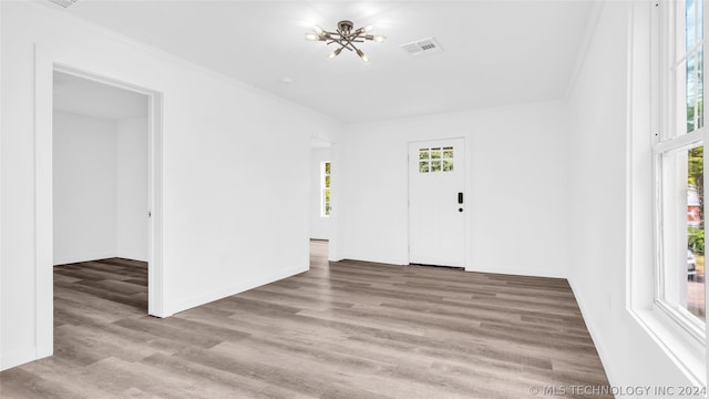 spare room with ornamental molding, wood-type flooring, and an inviting chandelier