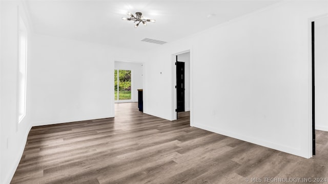 unfurnished room featuring wood-type flooring and a notable chandelier