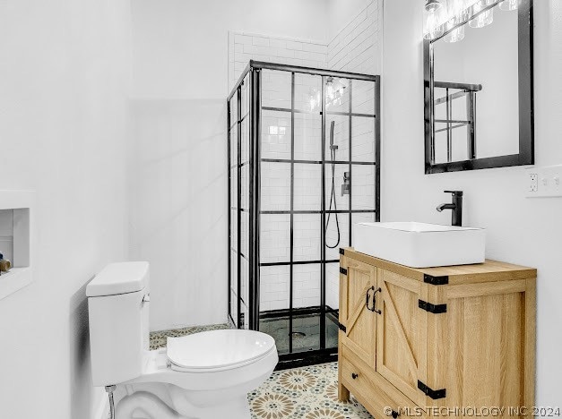 bathroom featuring a shower with door, vanity, tile patterned flooring, and toilet