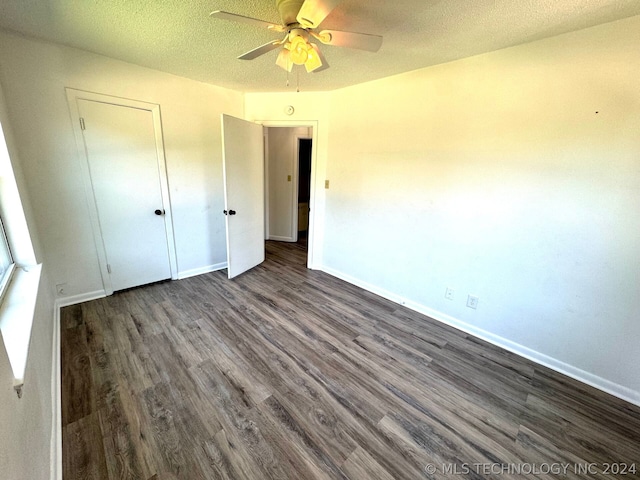 unfurnished bedroom with ceiling fan, dark wood-type flooring, a textured ceiling, and a closet