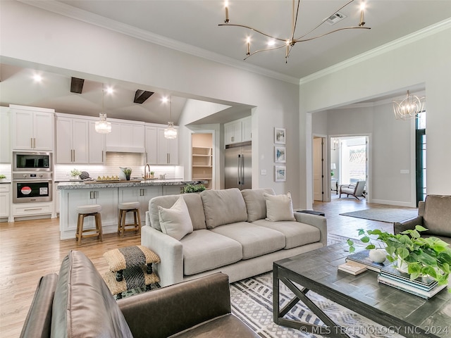 living room with a chandelier, sink, ornamental molding, and light hardwood / wood-style flooring