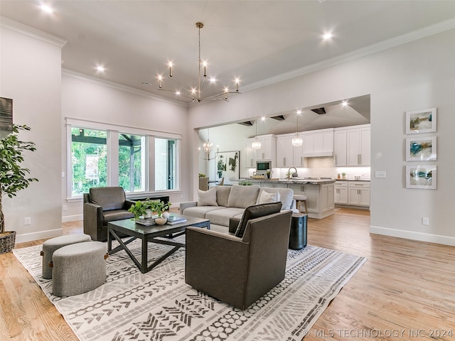 living room with light hardwood / wood-style floors, sink, crown molding, and a notable chandelier