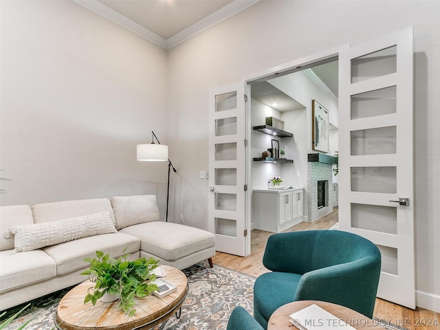 living room featuring crown molding, a brick fireplace, built in shelves, and light hardwood / wood-style flooring