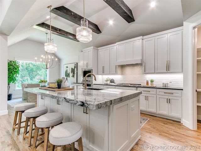 kitchen featuring lofted ceiling with beams, a center island with sink, light hardwood / wood-style flooring, white cabinets, and sink