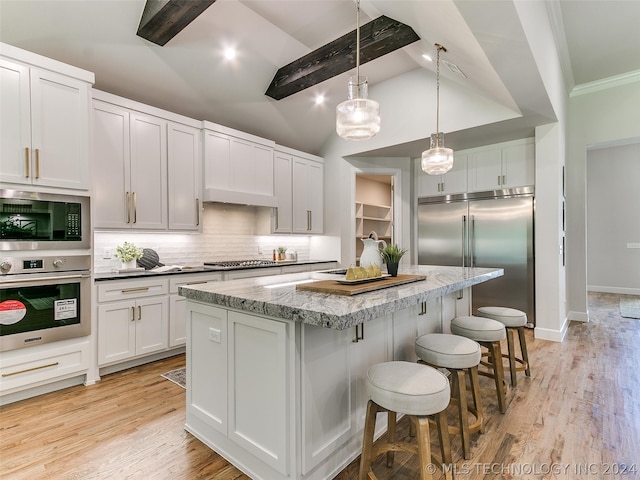 kitchen with light hardwood / wood-style floors, tasteful backsplash, built in appliances, a kitchen island, and white cabinetry