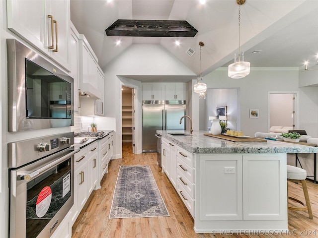 kitchen featuring pendant lighting, white cabinetry, a kitchen island with sink, built in appliances, and extractor fan