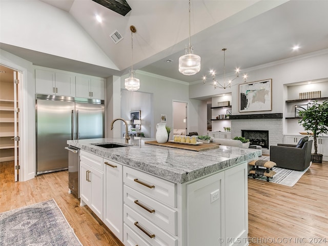 kitchen with a center island with sink, light hardwood / wood-style flooring, a fireplace, and white cabinetry