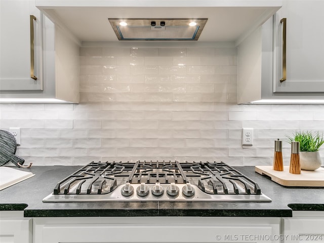 interior space with stainless steel gas cooktop, white cabinets, and tasteful backsplash