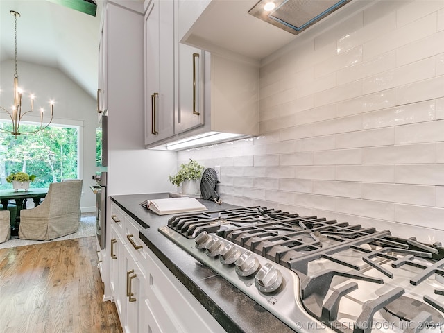 kitchen with light hardwood / wood-style floors, tasteful backsplash, vaulted ceiling, and appliances with stainless steel finishes