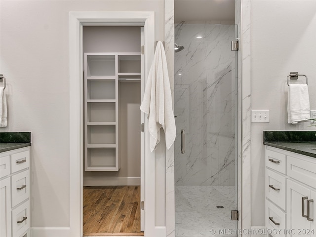 bathroom with a shower with shower door, hardwood / wood-style floors, and vanity