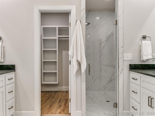 bathroom featuring vanity, a shower with shower door, and wood-type flooring