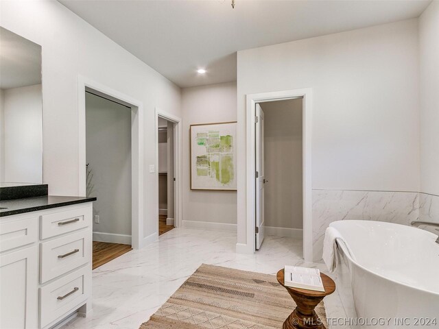 bathroom featuring a washtub, vanity, and tile floors