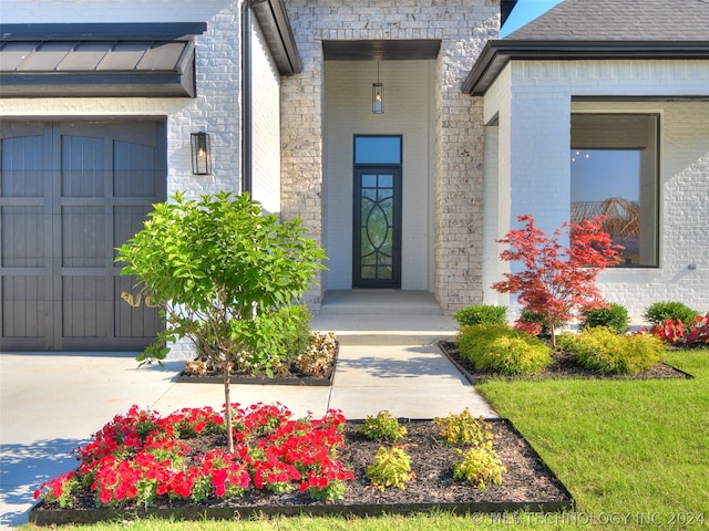 view of exterior entry with a garage and a yard