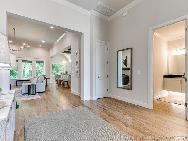 interior space with ornamental molding, light hardwood / wood-style floors, and a chandelier