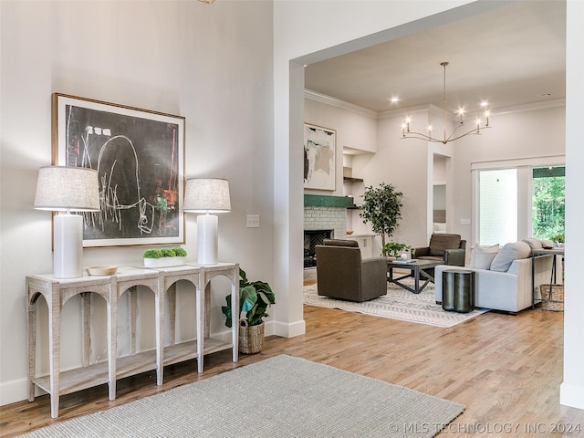 living room featuring wood-type flooring, a chandelier, a fireplace, and crown molding