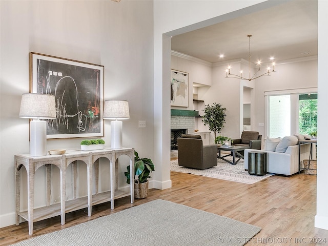 interior space with an inviting chandelier, ornamental molding, a fireplace, and light hardwood / wood-style flooring