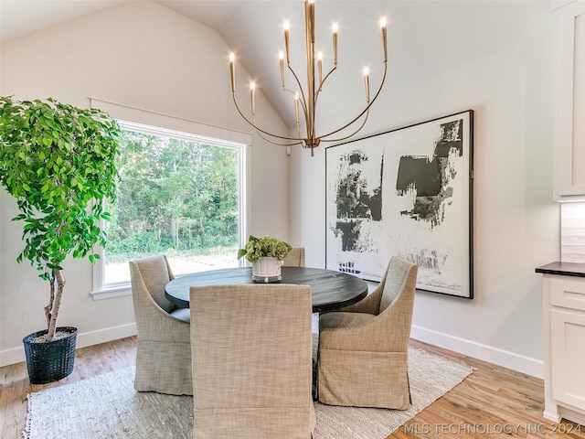 dining area with light hardwood / wood-style floors, a wealth of natural light, lofted ceiling, and a chandelier