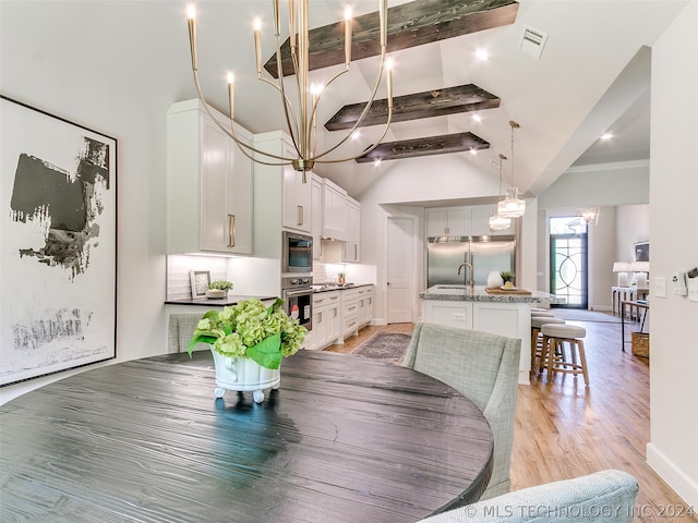 dining area with beam ceiling, light hardwood / wood-style floors, and a high ceiling