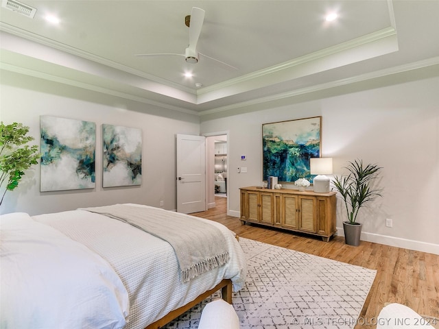 bedroom with crown molding, light hardwood / wood-style flooring, a raised ceiling, and ceiling fan