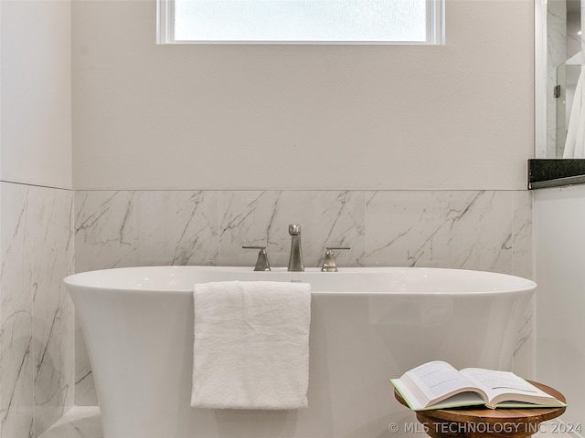 bathroom featuring plenty of natural light and tile walls