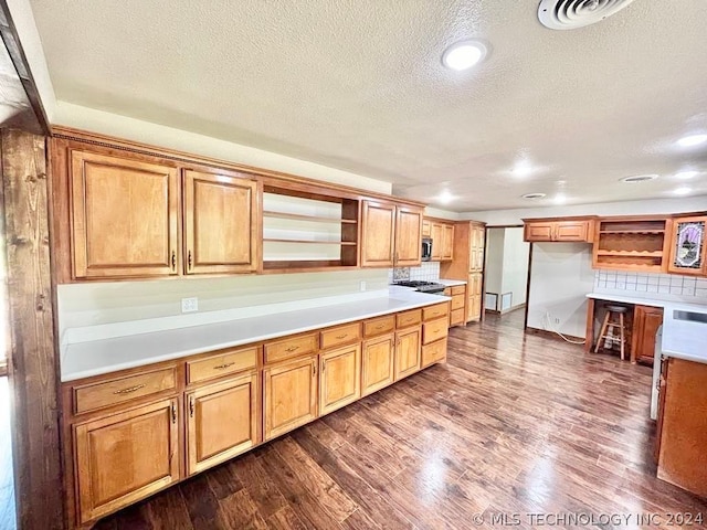 kitchen with appliances with stainless steel finishes, hardwood / wood-style flooring, and a textured ceiling