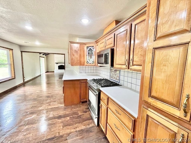 kitchen with tasteful backsplash, a textured ceiling, range with gas stovetop, and dark hardwood / wood-style floors