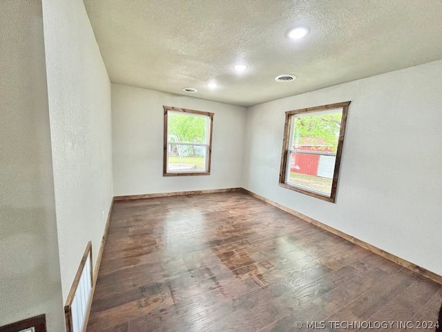 empty room featuring hardwood / wood-style flooring, plenty of natural light, and a textured ceiling