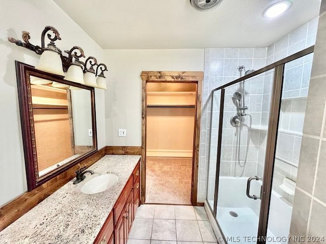 bathroom featuring a shower with door, tile patterned flooring, and vanity