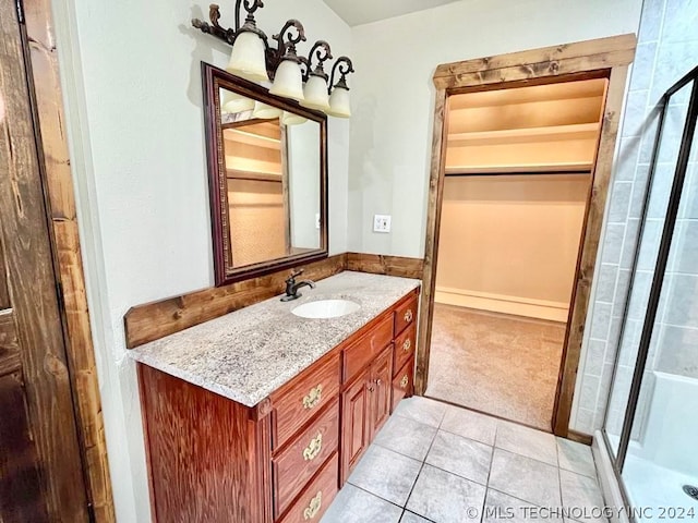 bathroom with tile patterned flooring, a shower with door, and vanity