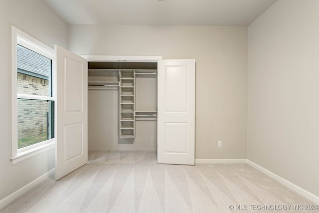 unfurnished bedroom with light colored carpet and a closet