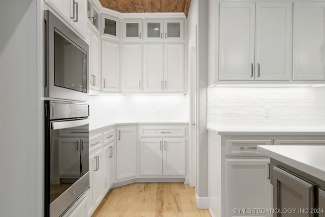 kitchen with backsplash, light hardwood / wood-style flooring, white cabinets, and appliances with stainless steel finishes