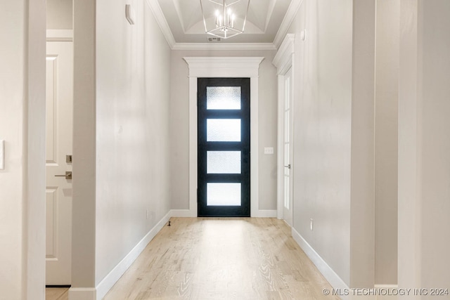 entryway featuring a chandelier, ornamental molding, and light wood-type flooring