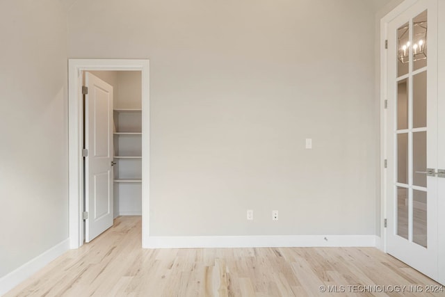 empty room with a notable chandelier and light wood-type flooring