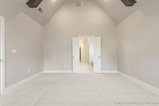 carpeted spare room with ceiling fan and high vaulted ceiling