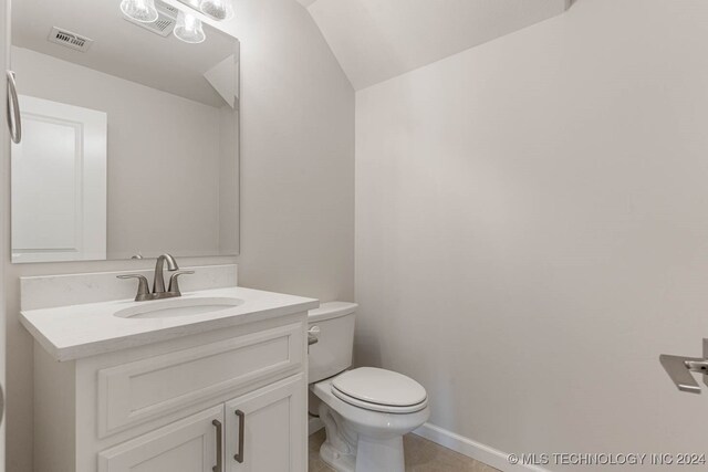 bathroom featuring vanity, toilet, and vaulted ceiling