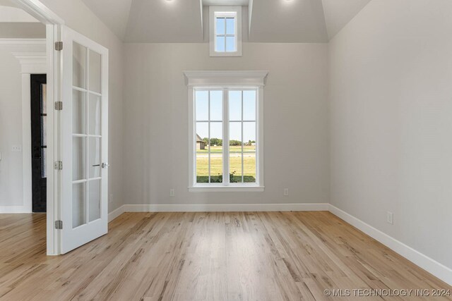 unfurnished room featuring lofted ceiling and light hardwood / wood-style floors