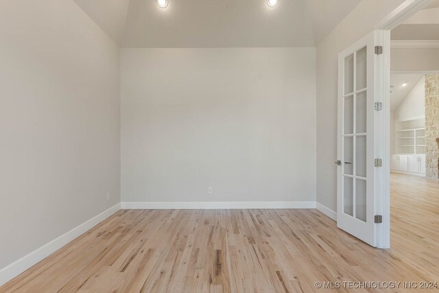 empty room with vaulted ceiling and light hardwood / wood-style floors