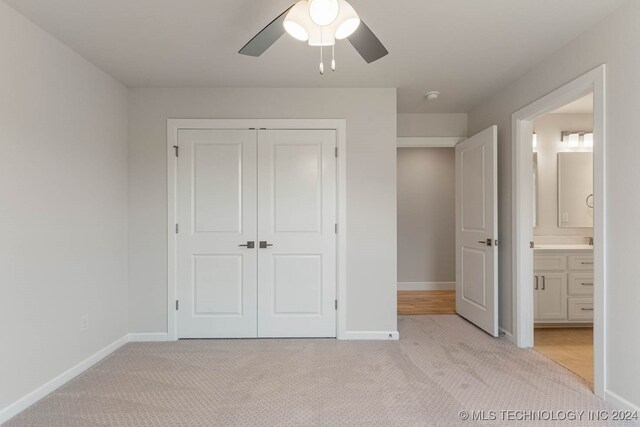 unfurnished bedroom featuring light colored carpet, ceiling fan, and a closet