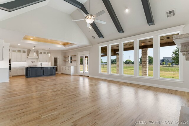 unfurnished living room with high vaulted ceiling, ceiling fan, sink, and light hardwood / wood-style flooring