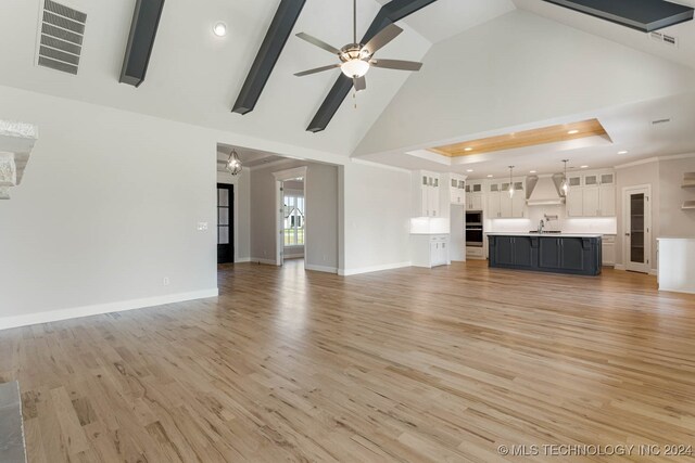 unfurnished living room featuring high vaulted ceiling, wood-type flooring, sink, and ceiling fan