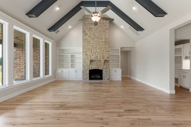 unfurnished living room featuring a fireplace, high vaulted ceiling, built in features, ceiling fan, and light hardwood / wood-style floors