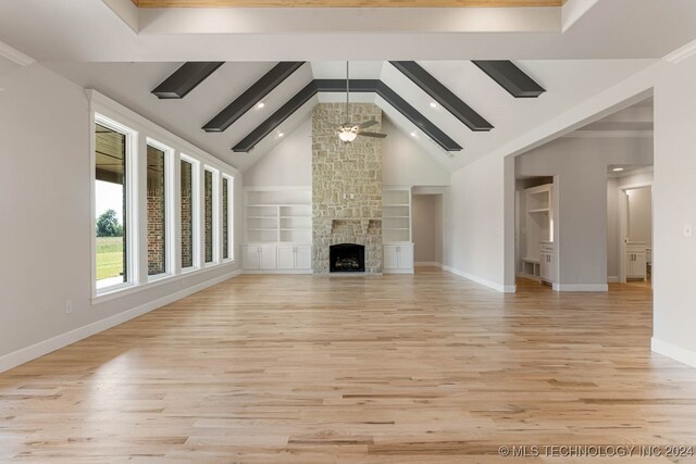 unfurnished living room with a stone fireplace, beam ceiling, light hardwood / wood-style floors, built in features, and ceiling fan