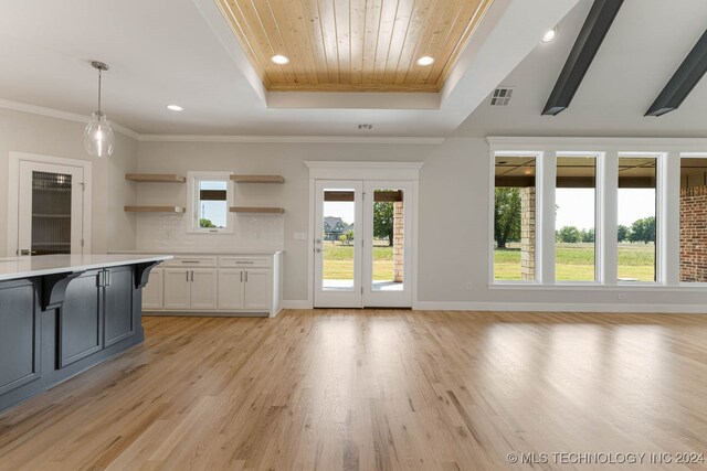 interior space with a tray ceiling, light hardwood / wood-style floors, and ornamental molding