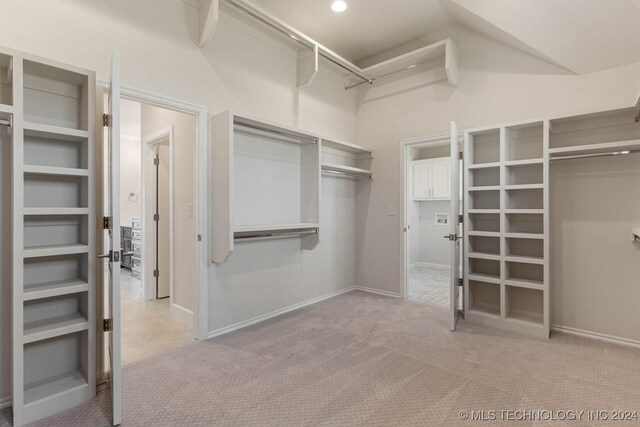 walk in closet with lofted ceiling and light colored carpet