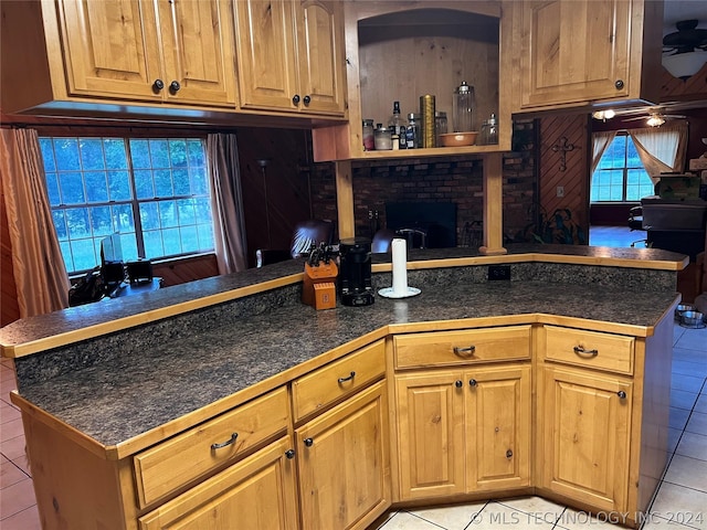 kitchen featuring a fireplace, kitchen peninsula, and light tile patterned floors