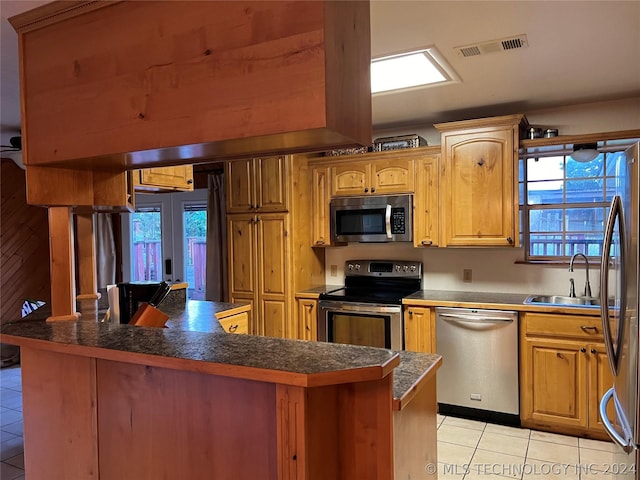 kitchen with stainless steel appliances, a wealth of natural light, sink, and light tile patterned floors