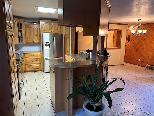 kitchen with light tile patterned floors, appliances with stainless steel finishes, hanging light fixtures, kitchen peninsula, and wood walls