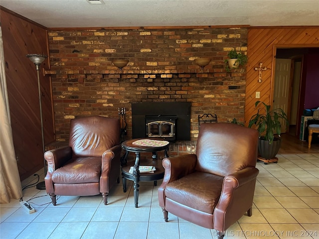 living area with light tile patterned floors, wood walls, ornamental molding, a textured ceiling, and a wood stove