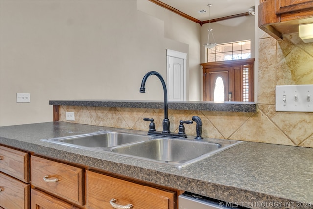 kitchen with sink, crown molding, backsplash, and hanging light fixtures